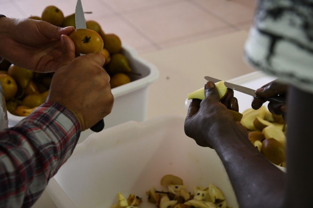 Le mani di due persone intente a pulire e tagliare delle pere